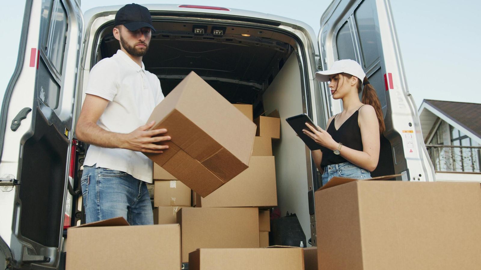 Delivery workers checking parcels beside a van