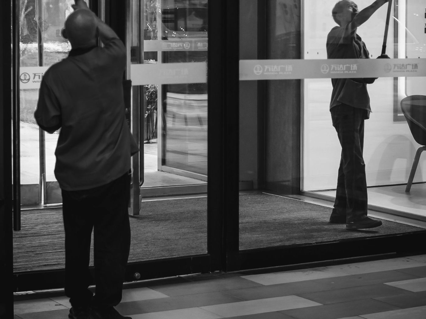Cleaners washing the glass entrance of a building